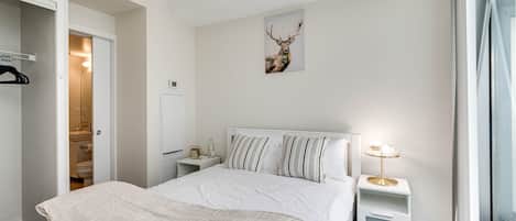A bedroom with a bed, bedside tables, a clock, a deer's head decoration, and a window.