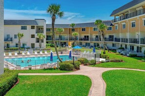 A hotel with a swimming pool, multiple balconies, and well-maintained lawns. - Oceanfront Escape in Ormond Beach! (Ormond Beach)