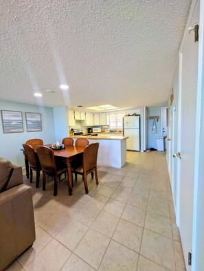 A compact living space with a dining area, kitchenette, and a door leading to another room. - Oceanfront Escape in Ormond Beach! (Ormond Beach)