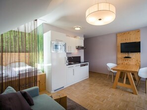 Un espacio habitable compacto con kitchenette, comedor y zona de estar.