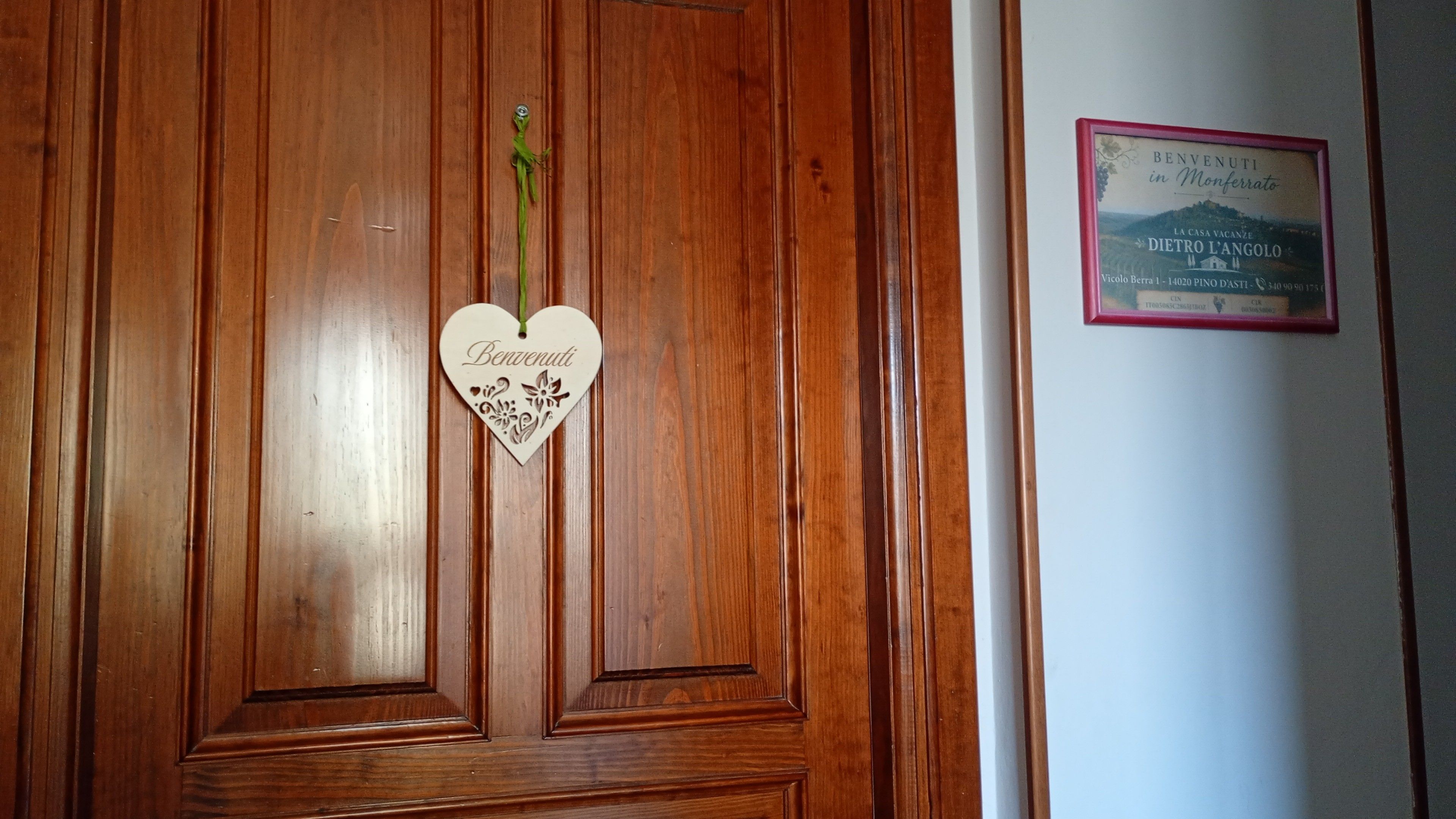 Eine Holztür mit einem herzförmigen Willkommensschild und einem gerahmten Willkommensschild an der Wand.