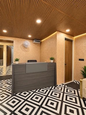A reception area with a reception desk, a wall-mounted air conditioner, and a potted plant.