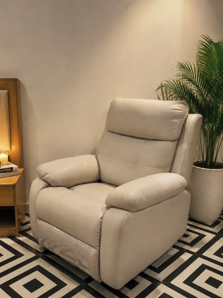 Un sillón de cuero color beige con un respaldo alto y reposabrazos, sobre un suelo con estampado blanco y negro.