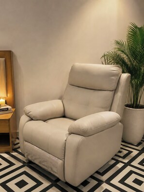 A beige leather armchair with a high backrest and armrests, positioned on a black and white patterned floor.