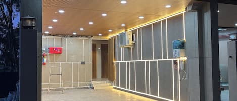 A modern building entrance with a tiled floor, a wooden ceiling, and recessed lighting.