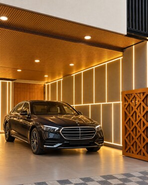 A black car parked in a modern indoor space with a wooden ceiling and illuminated wall panels. - Sukhmani Homestay (Indore)