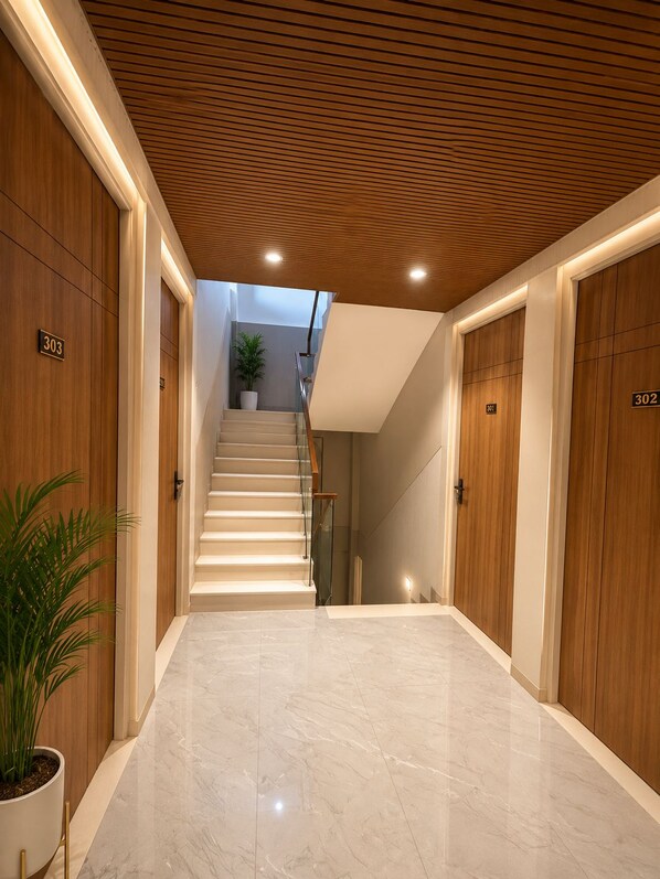 Un hall d’hôtel doté d’un sol en marbre, de lambris en bois et d’un escalier menant à un étage supérieur.