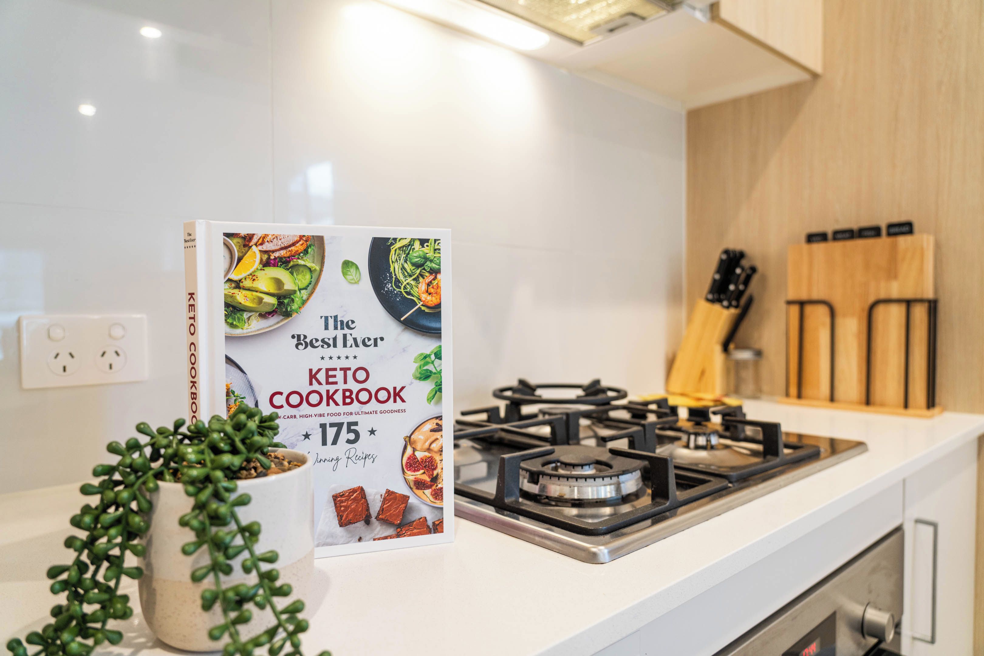 A kitchen counter with a cookbook titled 'The Best Ever Keto Cookbook' featuring 175 recipes.