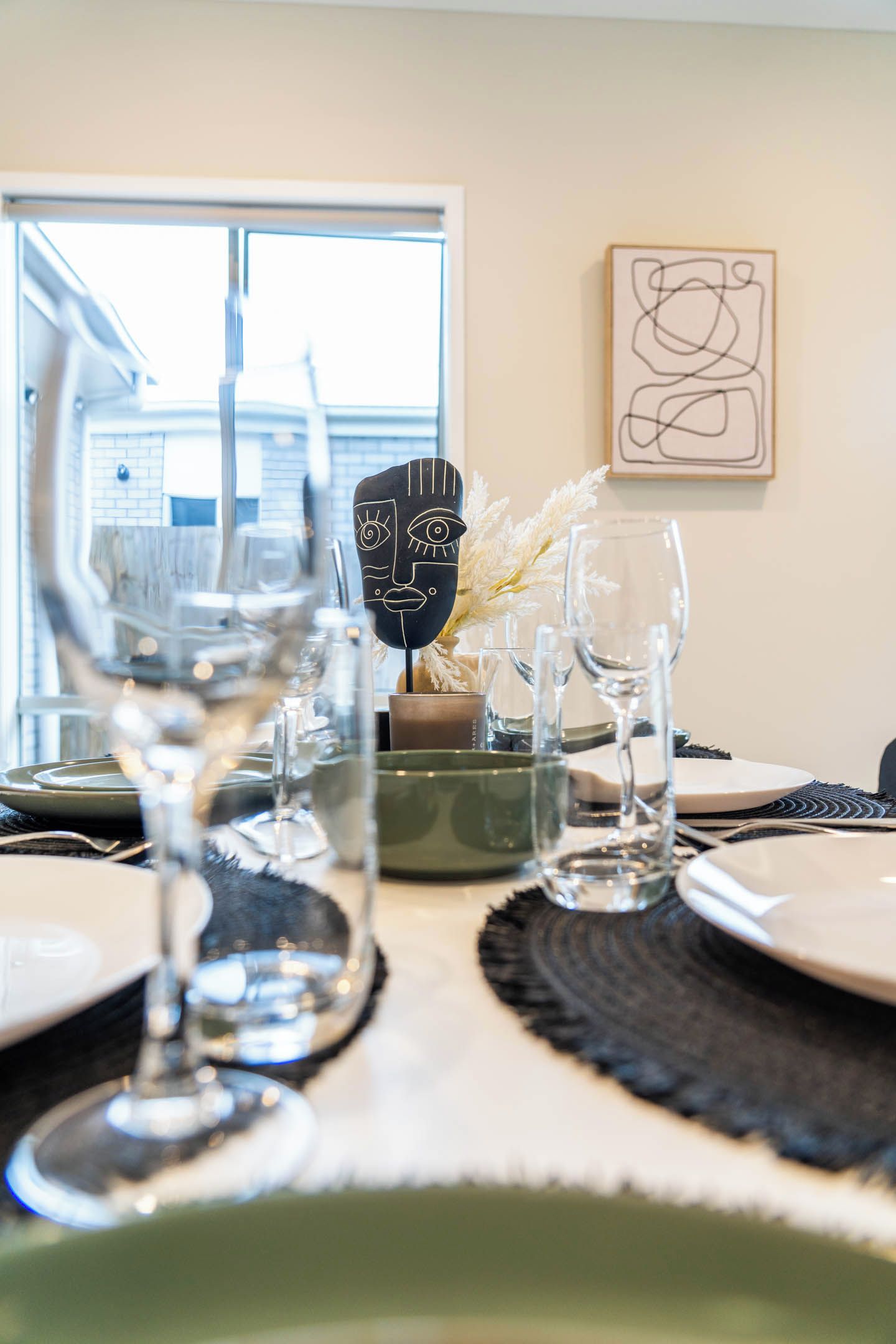 A dining table set with plates, glasses, and a decorative item.