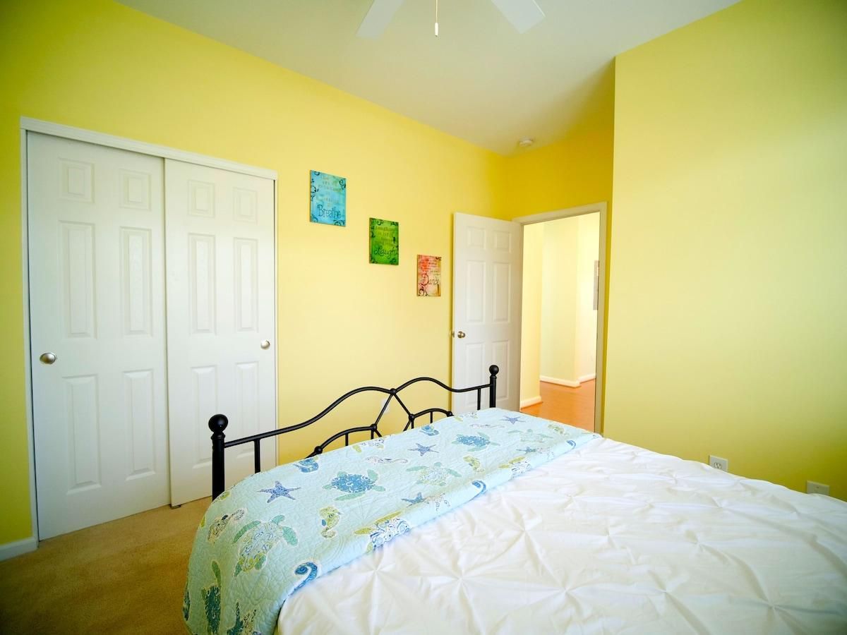 A bedroom with a bed, two white doors, and a ceiling fan.