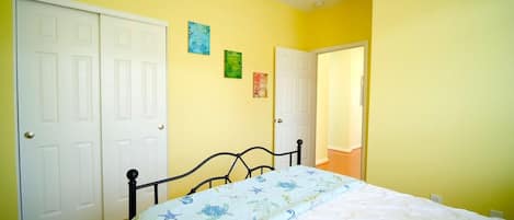 Une chambre à coucher avec un lit, deux portes blanches et un ventilateur de plafond.