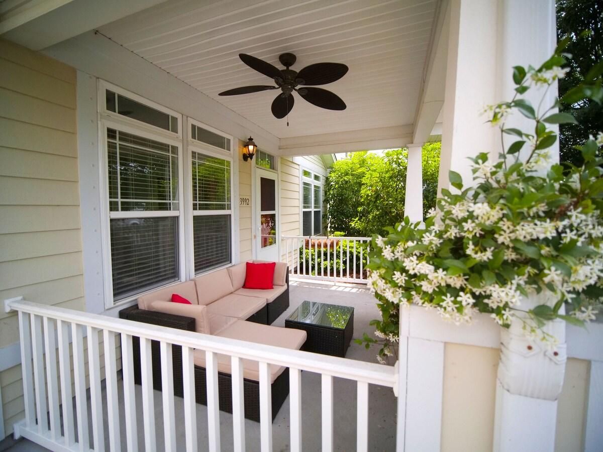 A covered porch with a ceiling fan, a sofa with cushions, and a small table.