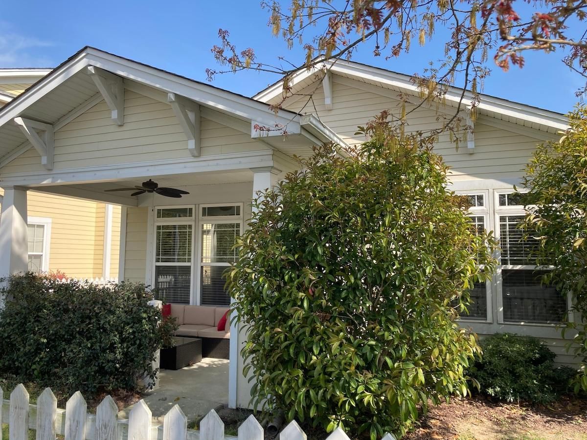 A residential house with a covered porch, a white picket fence, and a well-maintained lawn.