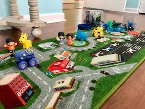 A play mat with toy figures and vehicles, a small toy bus, and a toy building. - Barb’s Stylish Digs: Modern Home+ Prime Location! (North Charleston)