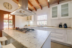 A modern kitchen with a central island, white cabinetry, and a built-in stove. - Finca Reig – Vacation Home with Private Pool near Pollensa Beach (Illes Balears)