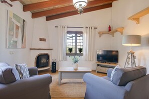 A living room with a fireplace, a television, and a sofa. - Finca Reig – Vacation Home with Private Pool near Pollensa Beach (Illes Balears)