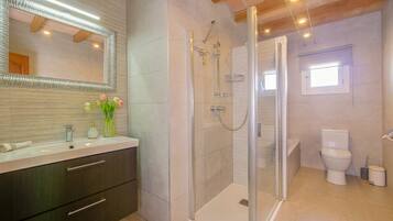 A modern bathroom with a glass-enclosed shower, a vanity with a mirror, and a toilet.
