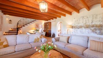 A spacious living area with a high wooden ceiling, a staircase, and a dining area.