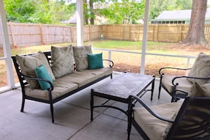 Ein überdachter Patio-Bereich mit einer Couch und einem Tisch.