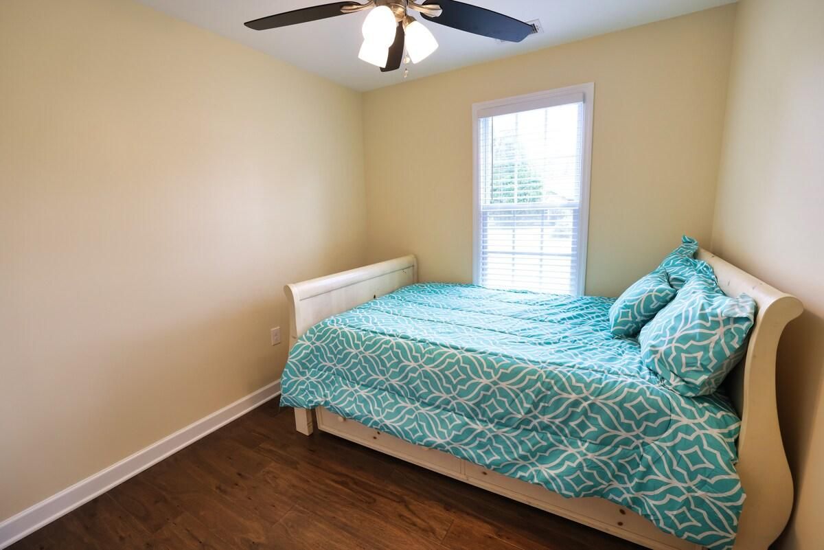 A bedroom with a single bed, a ceiling fan, and a window.
