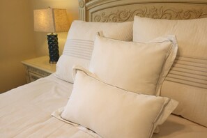 Ein Bett mit Kopfteil, zwei Kissen und ein Nachttisch mit Lampe.