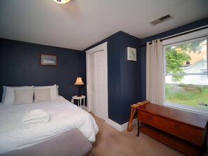 Une chambre à coucher avec un lit, une table de chevet, une lampe et une vue sur l’extérieur.