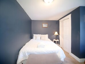 A bedroom with a bed, a bedside lamp, a framed picture on the wall, and a door. - Janelle’s Cottage: Walk to Brewery+Relax on Patio! (North Charleston)