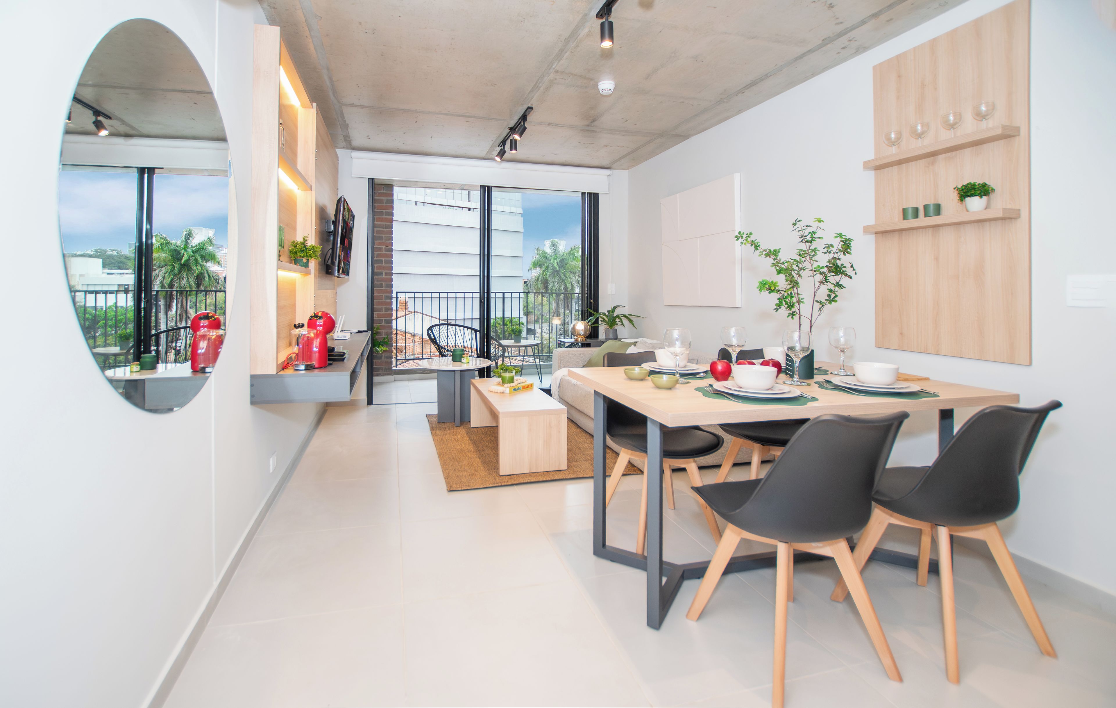 A modern kitchen with a dining area, featuring a large window, a built-in oven, and a coffee machine.
