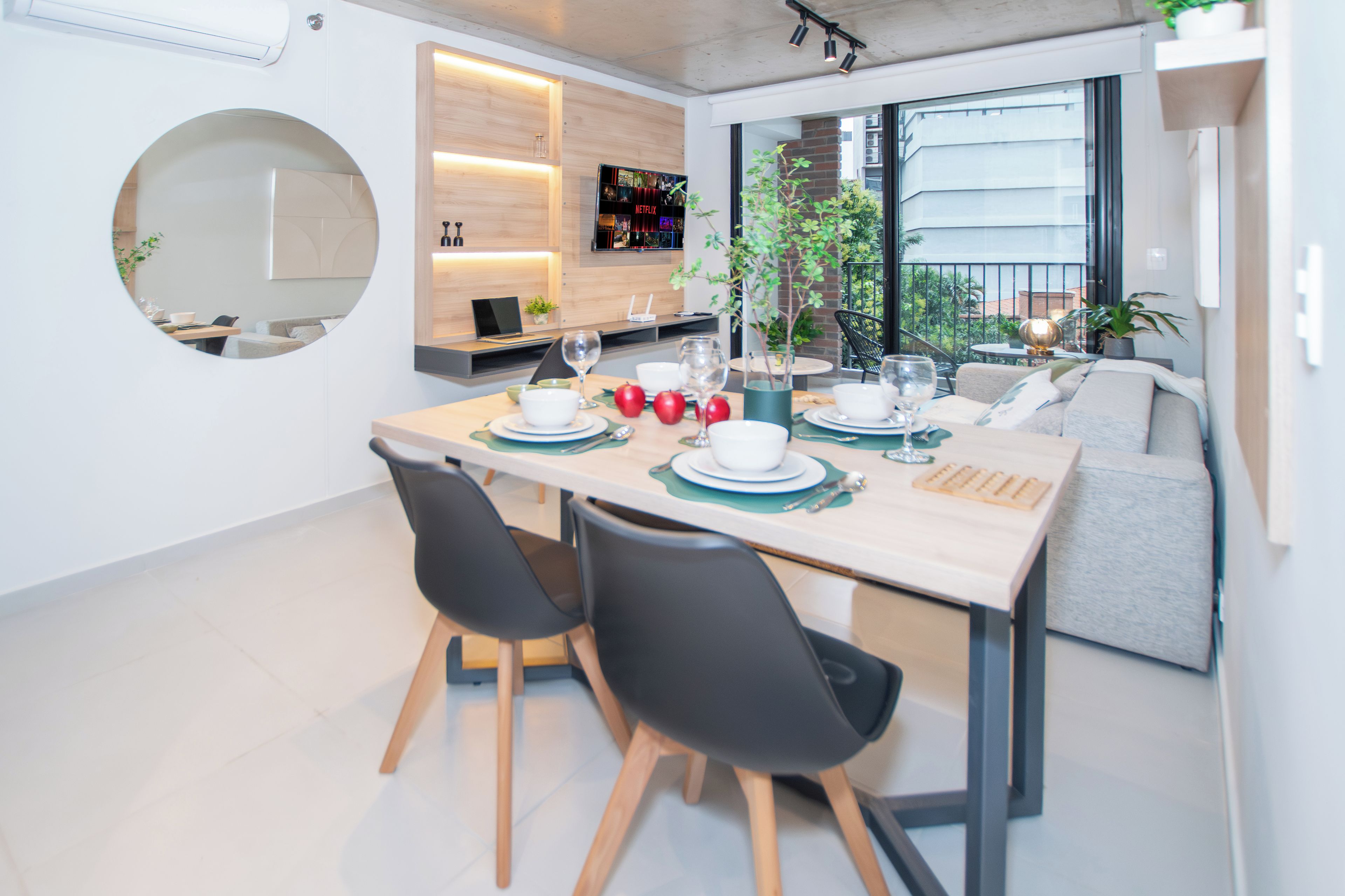A modern dining area with a round table, black chairs, and a view of the outdoors.