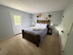Ein Schlafzimmer mit Bett, Tür, Nachttisch und Kleiderschrank.