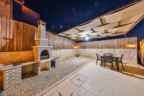 An outdoor patio area with a brick fireplace, a stone wall, and a table with chairs. - Serene 1-bedroom Villa With Private Pool in Gelemiş (Kaş)