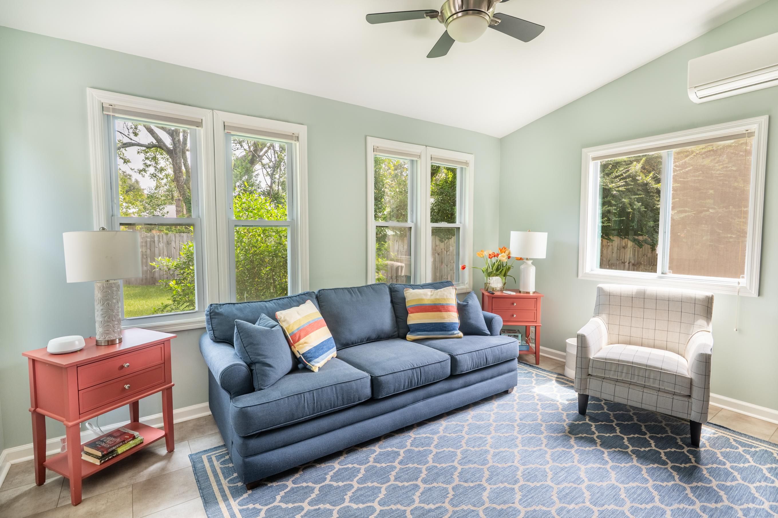 A living room with a blue sofa, two side tables, a chair, and a patterned rug.