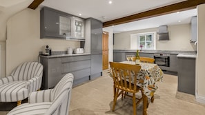 A modern kitchen with grey cabinets, a dining table with chairs, and a window. - The Snug at Arlington Mill - Couple's Escape Bibury, Cotswolds (Bibury)