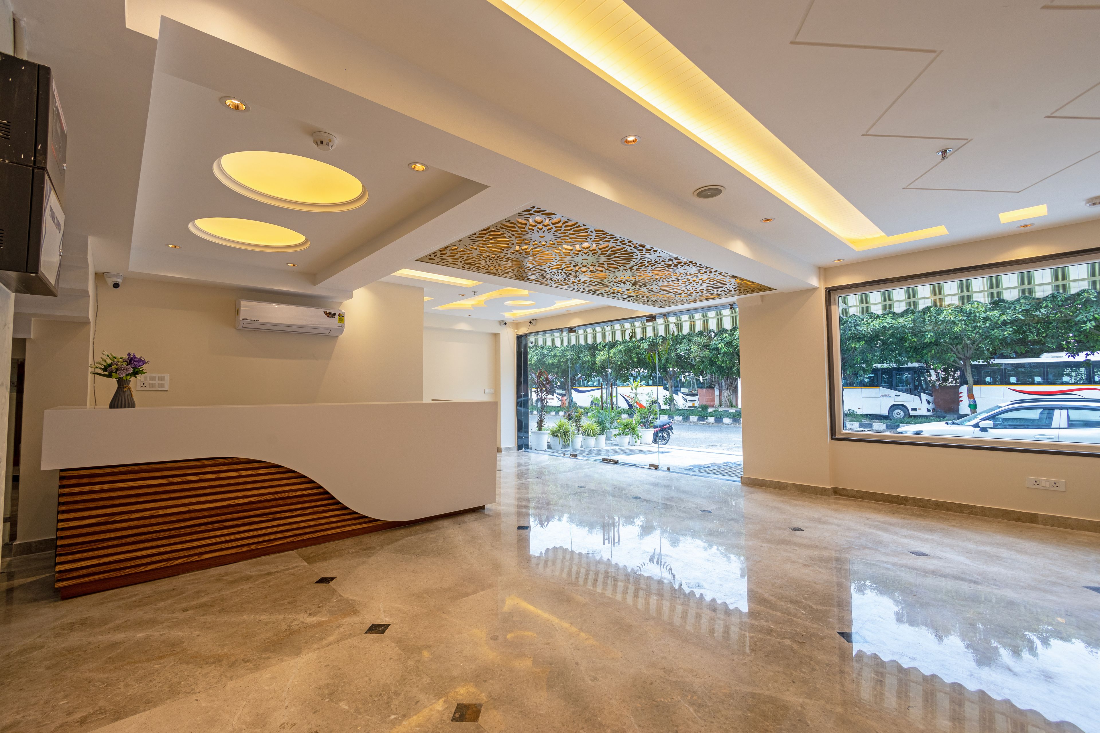 Een moderne receptie met een houten balie, een plafond met inbouwverlichting en een groot raam met uitzicht op de straat.