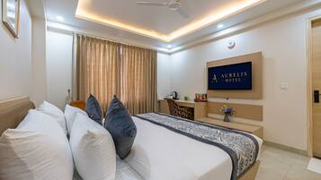 A hotel room with a bed, a desk, a television, and a ceiling fan.