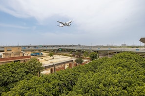 An airport runway with an airplane in flight, surrounded by airport infrastructure and greenery. - Aurelis Hotel By RMR (New Delhi)