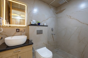 Ein Badezimmer mit weißem Waschbecken, einem Spiegel, einer Toilette und einer Duschkabine.
