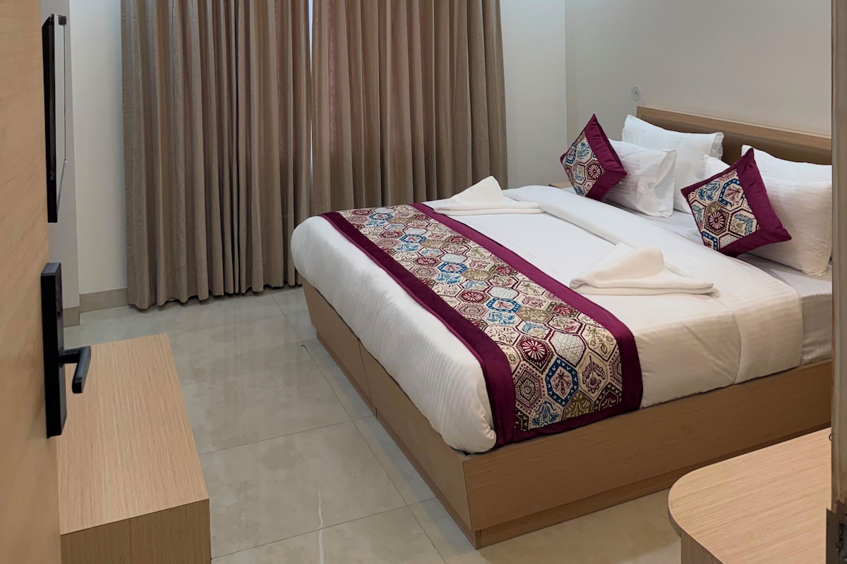 Ein modernes Hotelzimmer mit Bett, Vorhängen, Deckenventilator und Einbauleuchten.