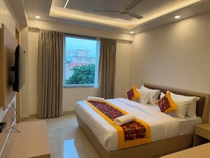 Ein Hotelzimmer mit Bett, Vorhängen, Deckenventilator und Fernseher.