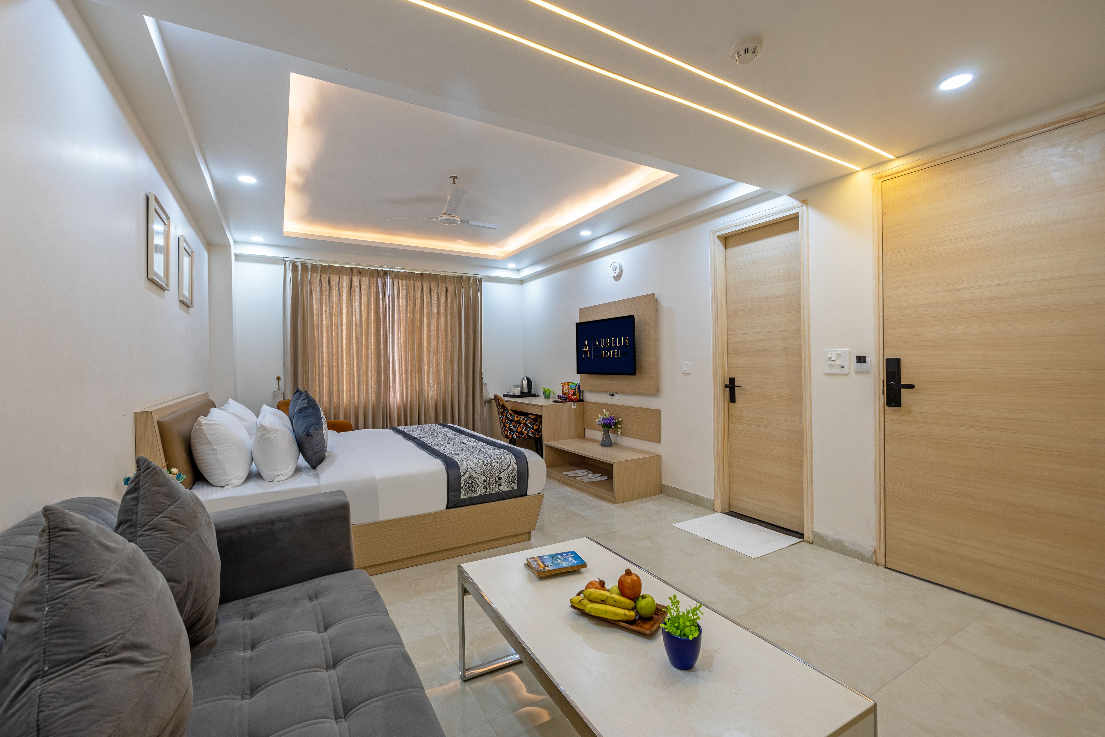 Een moderne hotelkamer met een bed, bank, televisie en een klein bureau.