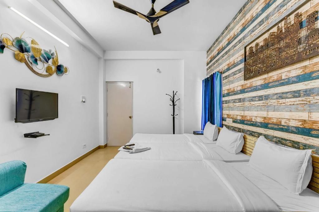 Habitación de hotel con cama, televisor, perchero y un panel decorativo en la pared.