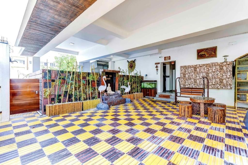 Un hall amplio con piso a cuadros, un banco de madera, pared de piedra y una estatua de un ave.