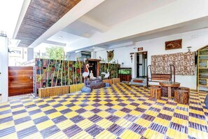 Un hall amplio con piso a cuadros, un banco de madera, pared de piedra y una estatua de un ave.