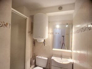 Ein Badezimmer mit Toilette, Waschbecken und Warmwasserbereiter.