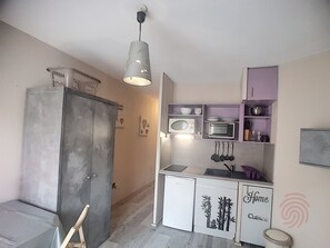 Een kleine keuken met een koelkast, magnetron en een spoelbak.