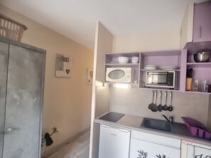 Eine kleine Küche mit Kühlschrank, Mikrowelle und Spüle.