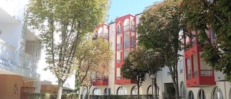 A courtyard with a pathway, benches, and a building with red and white architecture.