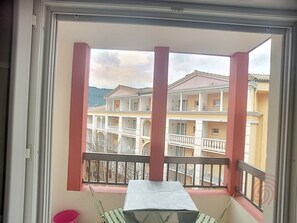 En balkon med et bord og stole, der ud til et flere etagers byggeri med egne balkoner.