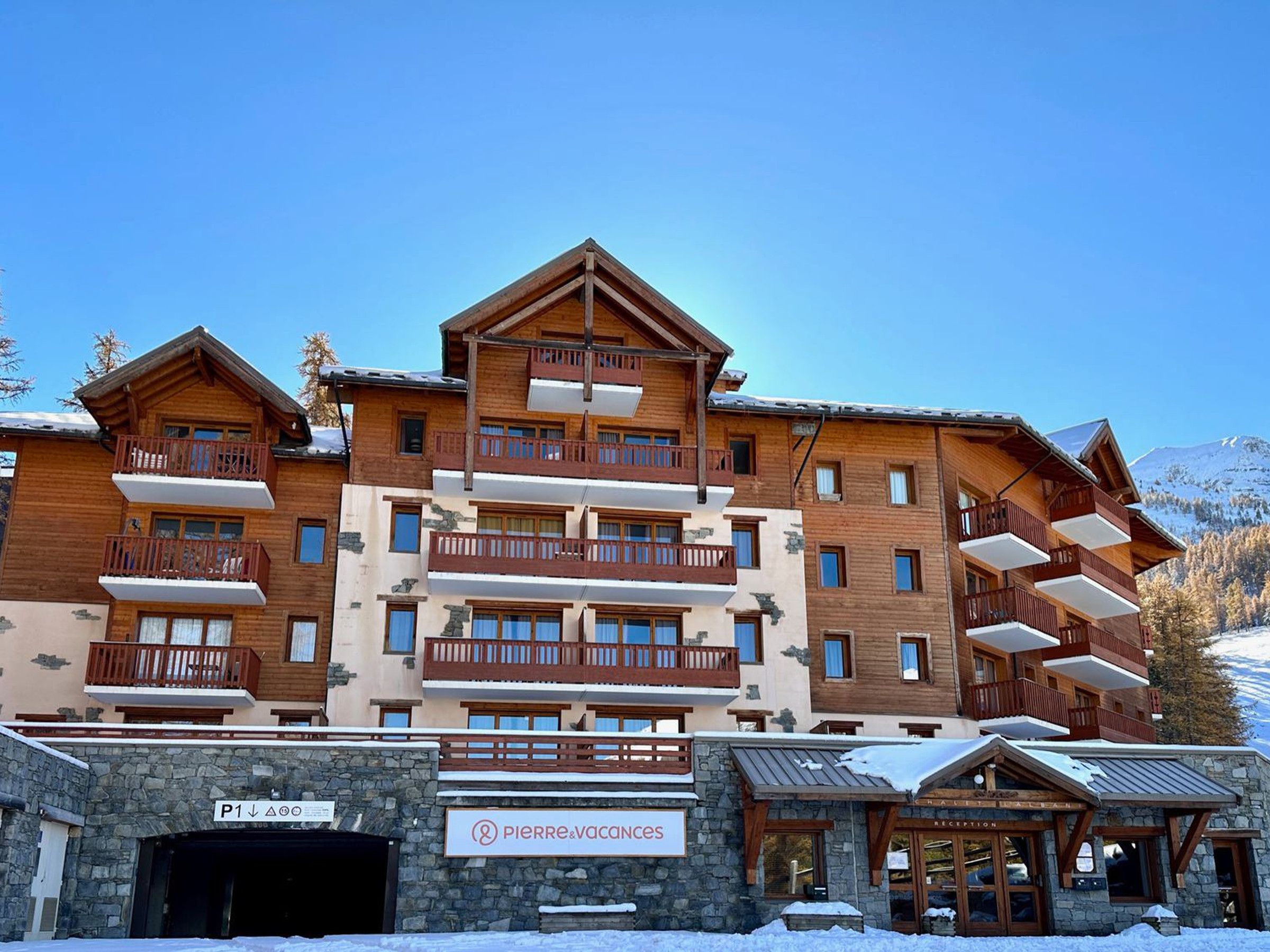 A multi-story hotel with balconies, a reception area, and a sign indicating 'Pierre & Vacances.'