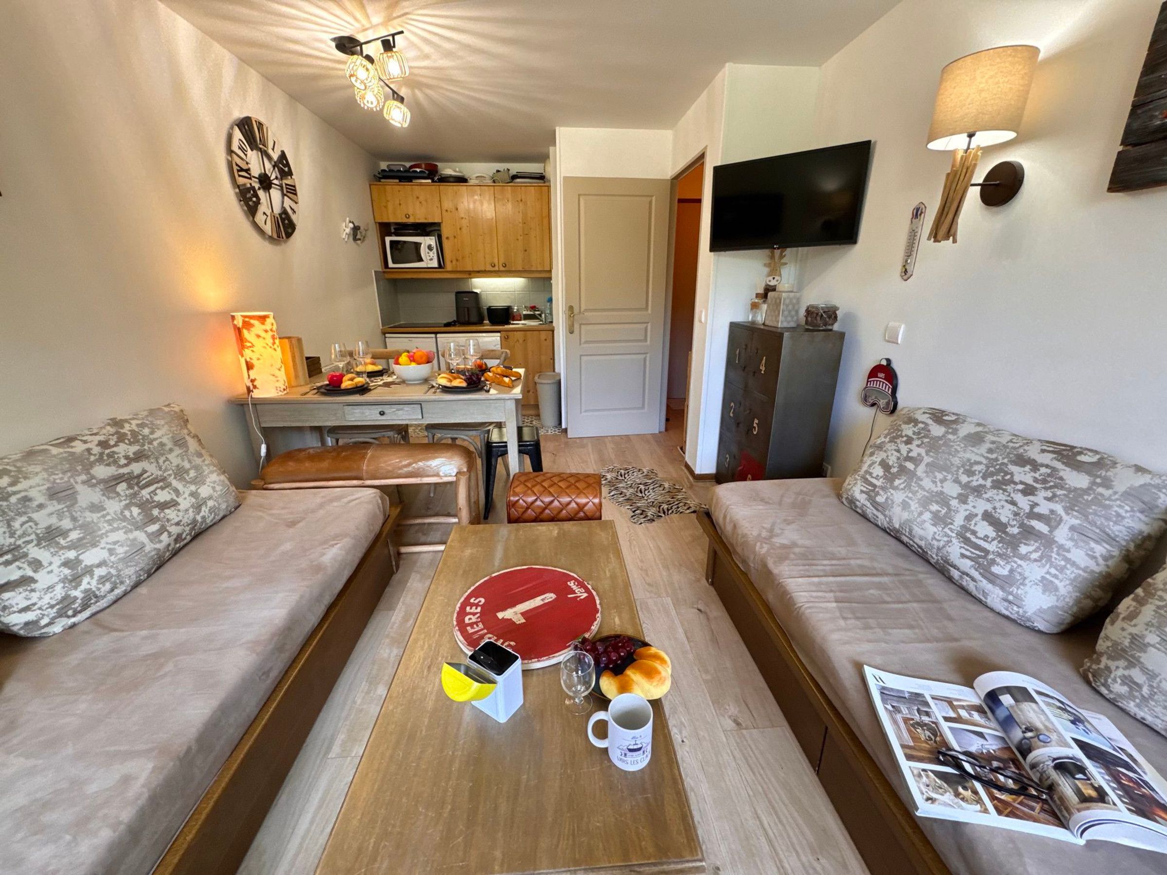 Un espacio habitable compacto con un sofá, una mesa de centro y una cocina al fondo.